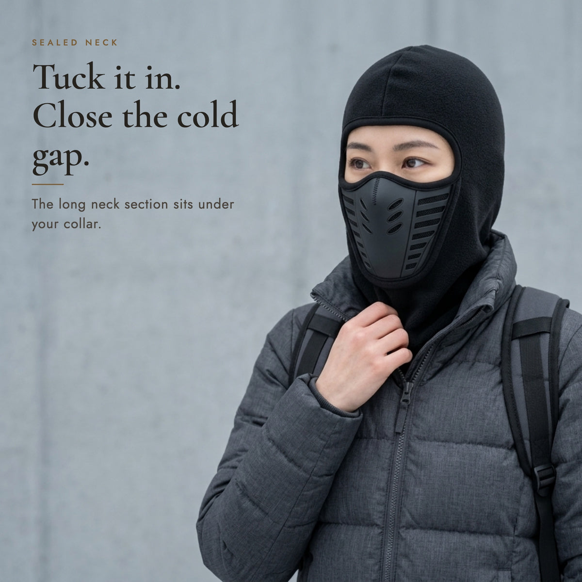 Woman tucking the long neck section of the balaclava into her jacket collar, headline Tuck it in. Close the cold gap.